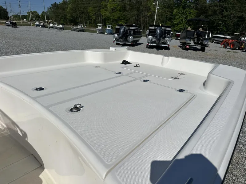 Slide: The Image of 2019 Mako Pro Skiff 17 boat deck in a gravel lot with other boats. - 4
