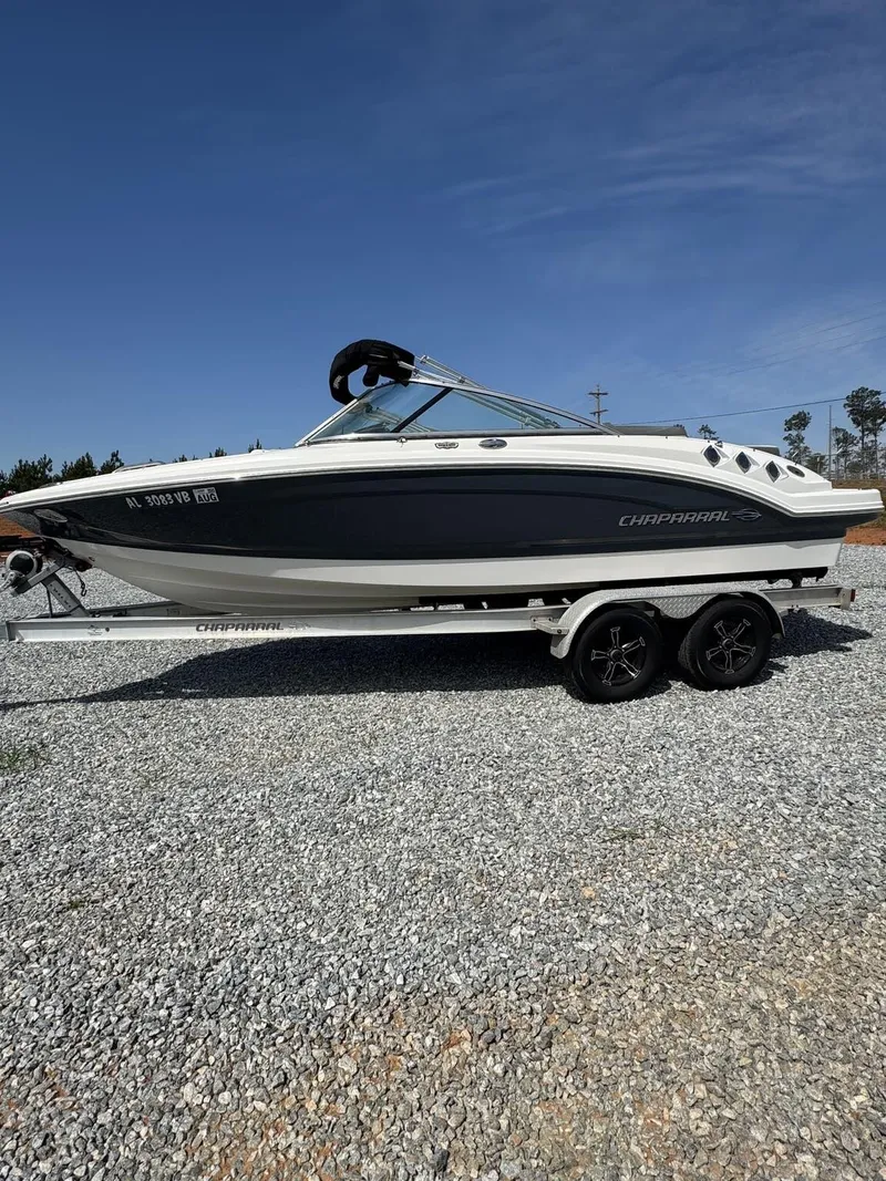 Slide: The Image of 2014 Chaparral 206 SSi boat on trailer, parked on gravel under clear blue sky. - 1
