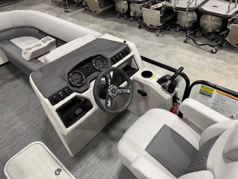 Slide: The Image of 2023 Sweetwater 2286 boat interior with steering console and seating in a showroom. - 12
