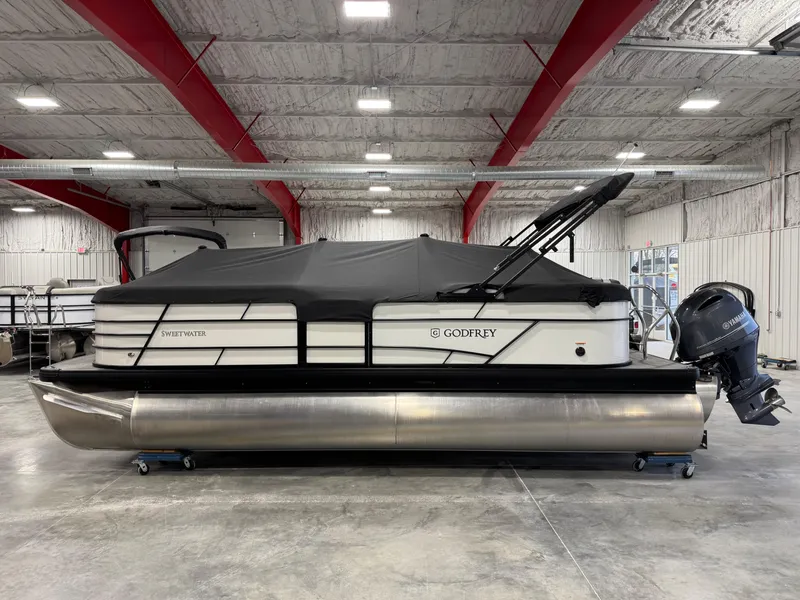 Slide: The Image of 2023 Sweetwater 2286 pontoon boat in a warehouse, covered and equipped with an outboard motor. - 14