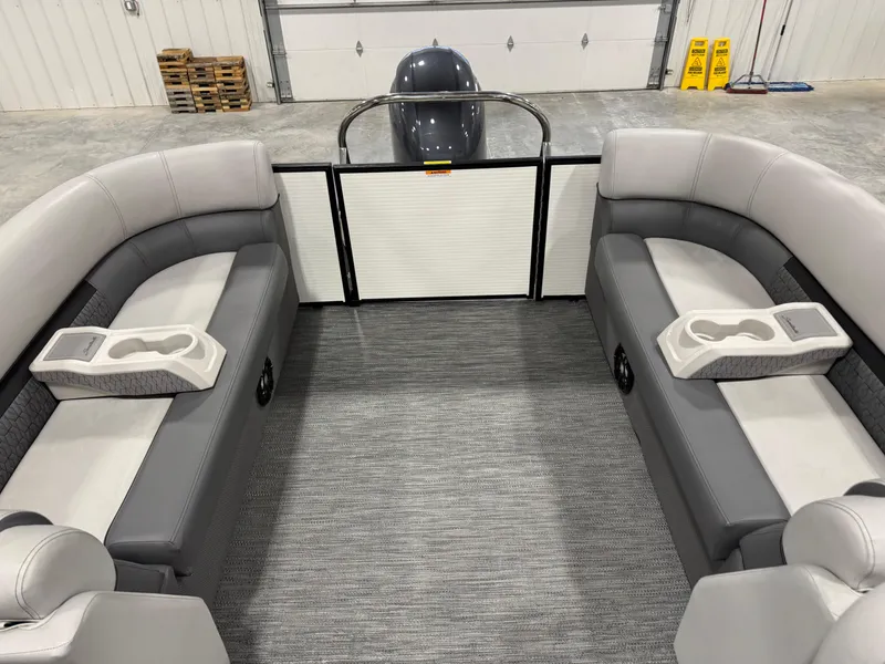 Slide: The Image of 2023 Sweetwater 2286 pontoon boat interior with gray seating and cup holders in a garage. - 7