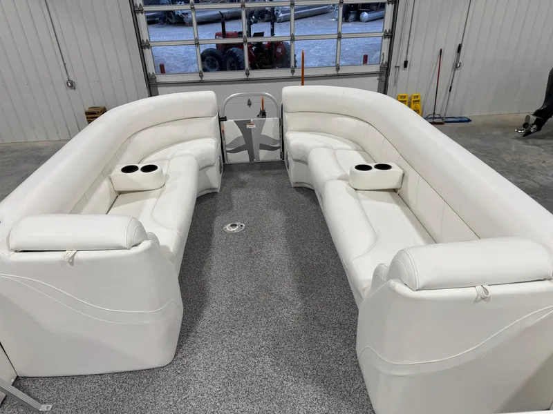 Slide: The Image of 2015 PlayCraft 2600 Sport Toon interior with white seating and cup holders in a garage. - 14