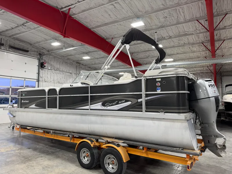 Slide: The Image of 2015 PlayCraft 2600 Sport Toon pontoon boat on trailer in indoor storage. - 3