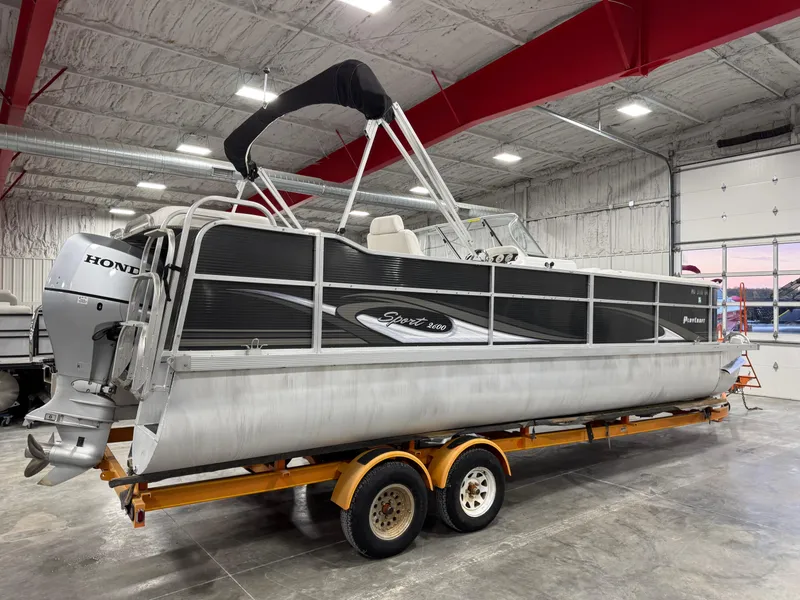 Slide: The Image of 2015 PlayCraft 2600 Sport Toon pontoon boat on trailer in indoor storage. - 4