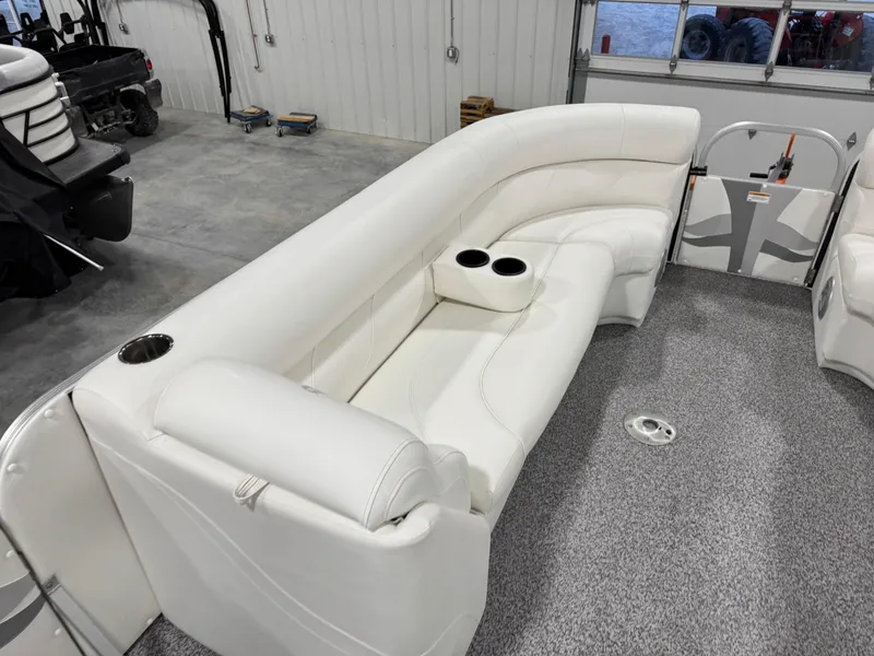 Slide: The Image of 2015 PlayCraft 2600 Sport Toon interior with white seating and cup holders in a garage. - 8