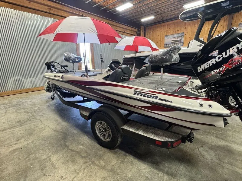 Slide: The Image of 2016 Triton 18 TrX boat with red and white umbrellas, displayed indoors. - 12