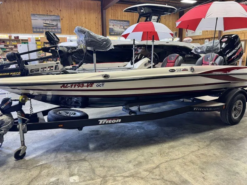 Slide: The Image of 2016 Triton 18 TrX boat on trailer in showroom with red and white umbrellas. - 13