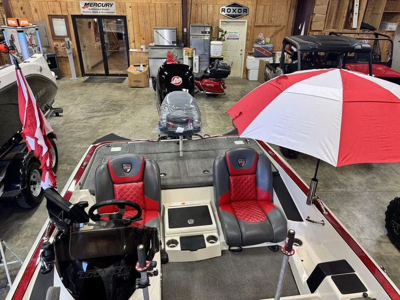 Slide: The Image of 2016 Triton 18 TrX boat with red and black seats, displayed indoors with a red and white umbrella. - 17