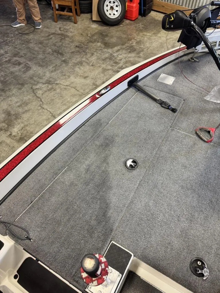 Slide: The Image of 2016 Triton 18 TrX boat interior with carpeted deck and fishing equipment. - 18