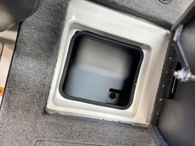 Slide: The Image of Open storage compartment in 2016 Triton 18 TrX boat, featuring gray carpeted interior. - 28