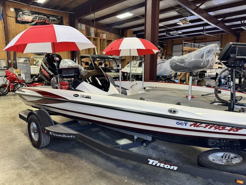 Slide: The Image of 2016 Triton 18 TrX boat in showroom with red and white umbrellas. - 7