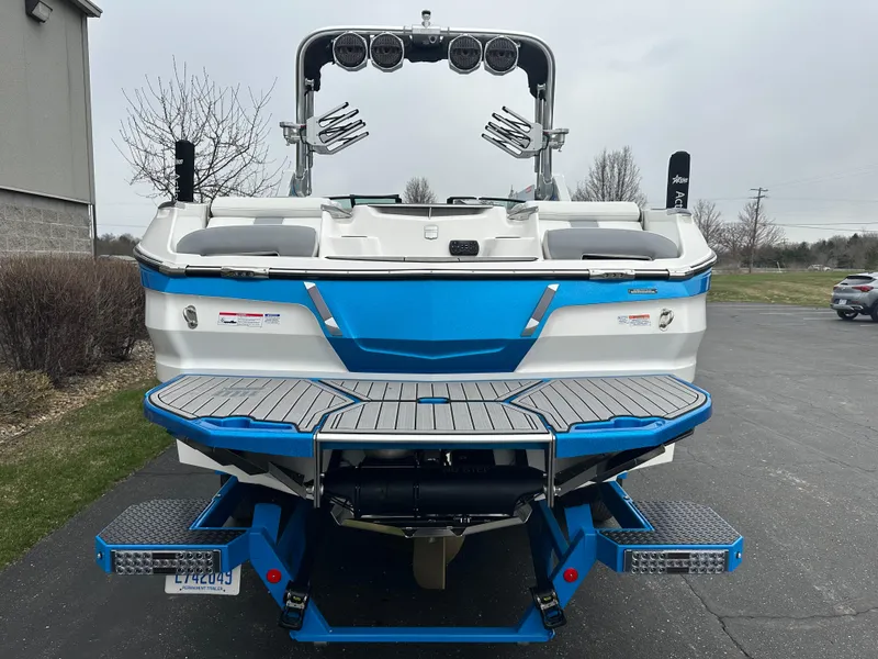 Slide: The Image of 2023 MasterCraft X24 boat, blue and white, rear view with swim platform and speakers. - 5