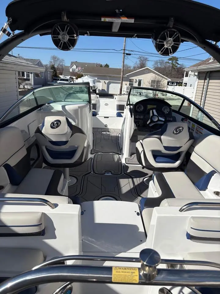 Slide: The Image of 2022 Hurricane SunDeck 2486 OB boat interior with seating and steering wheel, docked outdoors. - 4