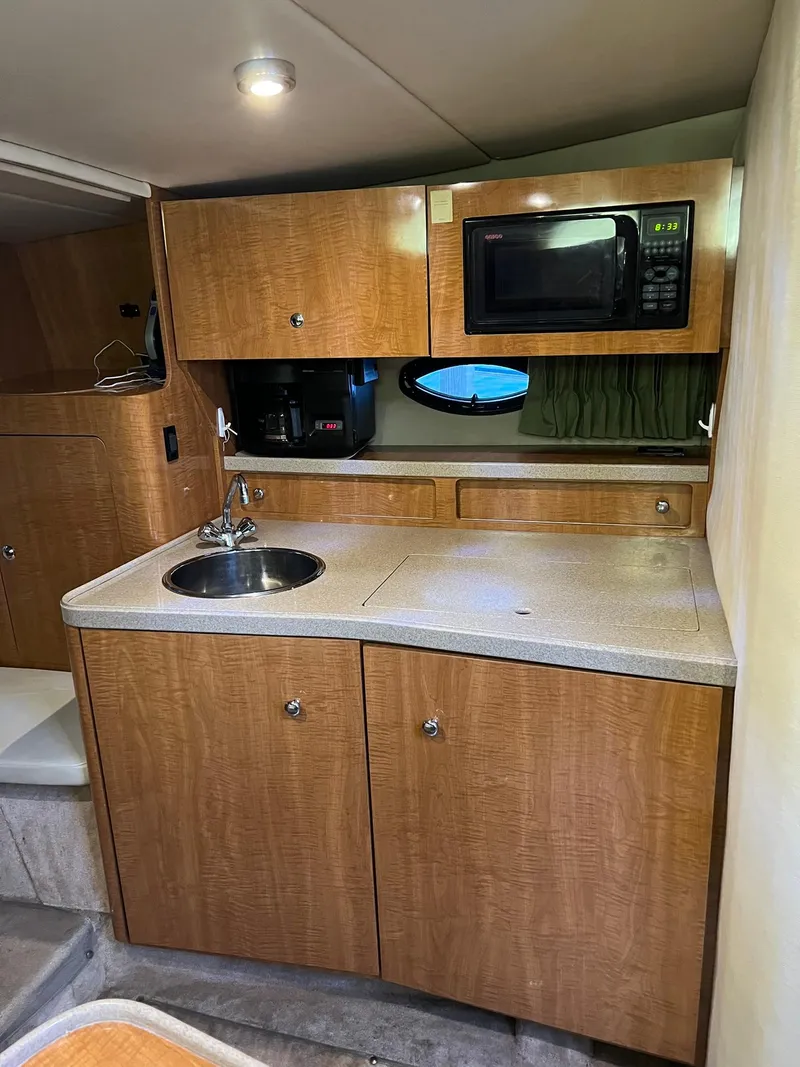 Slide: The Image of 2003 Regal Commodore 3260 boat kitchen with wood cabinets, sink, and microwave. - 9