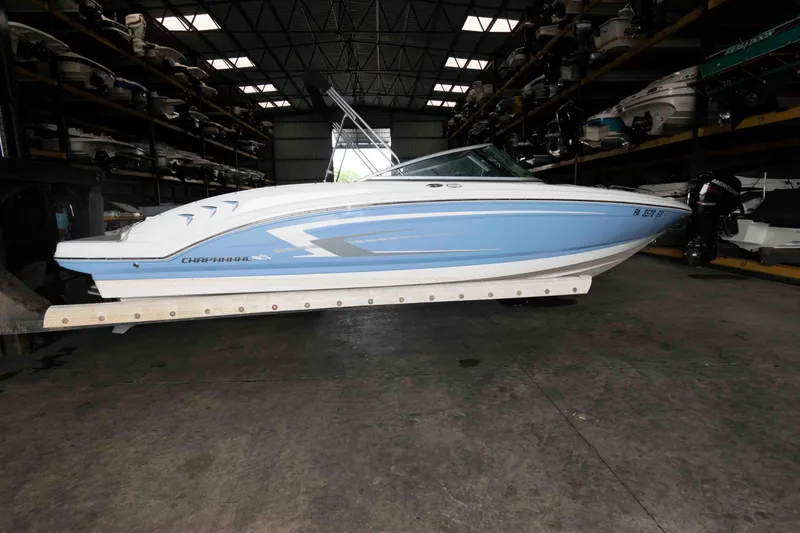 Slide: The Image of 2022 Chaparral 23 SSi boat in storage, side view, blue and white design. - 2