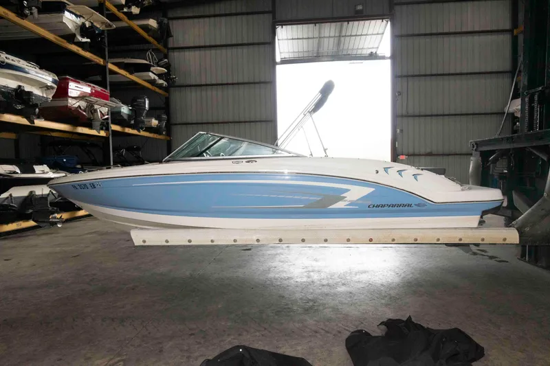 Slide: The Image of 2022 Chaparral 23 SSi boat in storage, blue and white design, side view. - 3