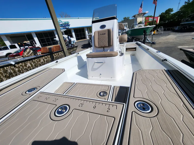 Slide: The Image of 2025 Avid 23FSX boat interior with tan deck and seating, displayed outdoors. - 15