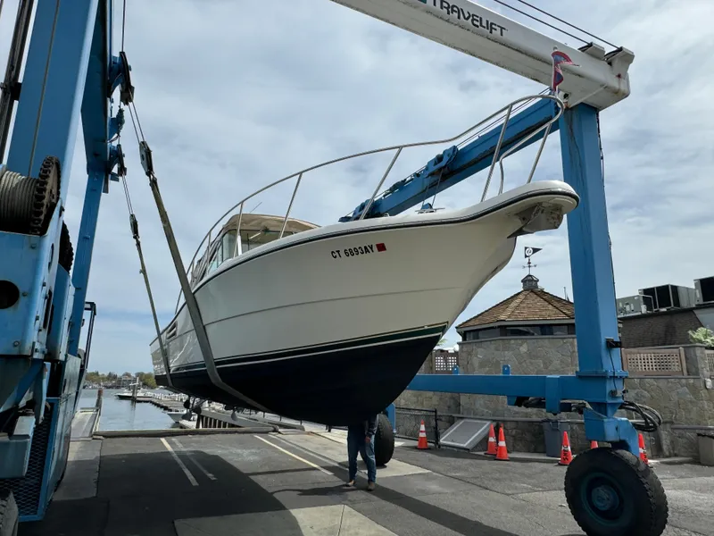 Slide: The Image of 2001 Pursuit 3000 Express boat being lifted by a travel lift at a marina. - 22