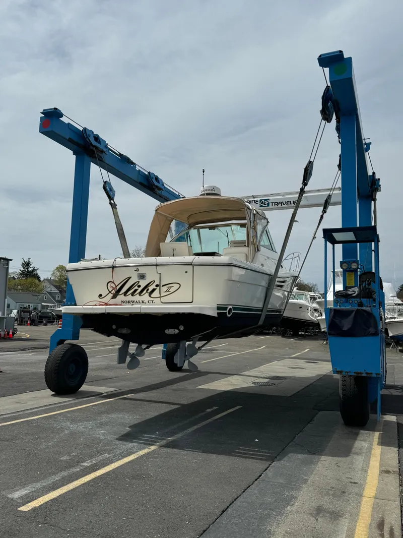 Slide: The Image of 2001 Pursuit 3000 Express boat lifted by a blue crane in a marina. - 27