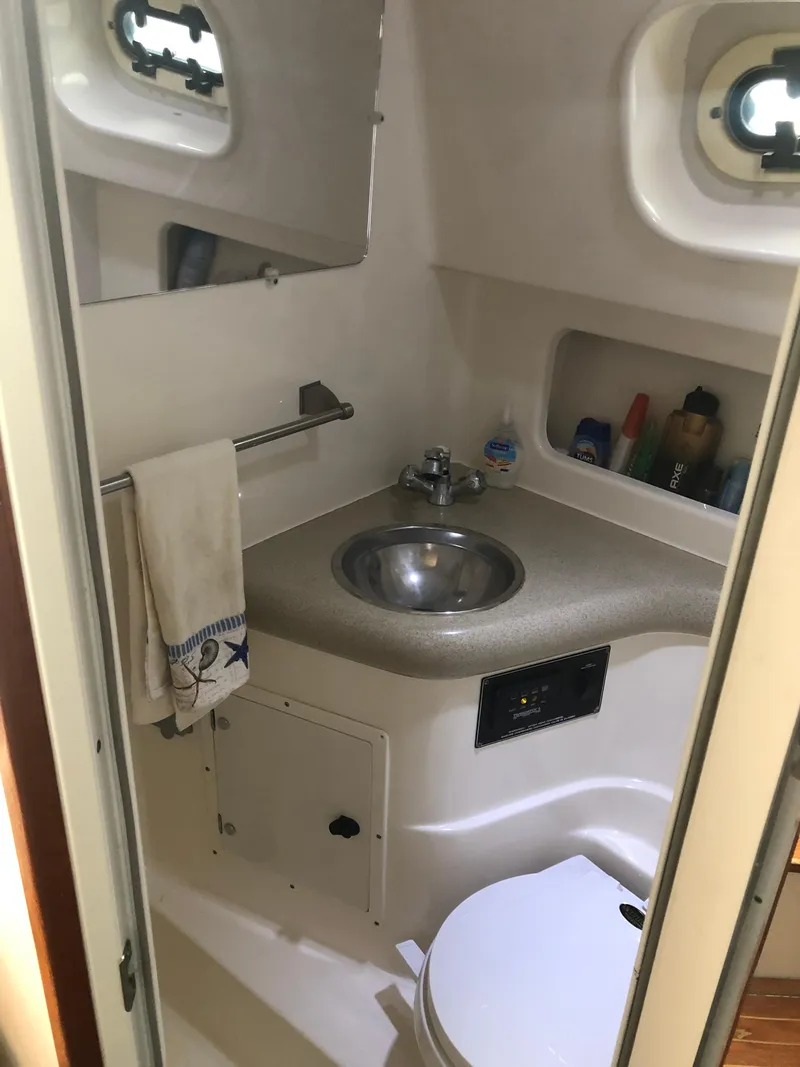 Slide: The Image of 2001 Pursuit 3000 Express boat bathroom with sink, toilet, and storage shelves. - 31