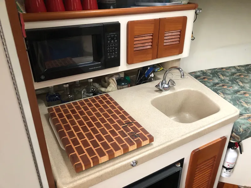 Slide: The Image of 2001 Pursuit 3000 Express boat kitchen with sink, microwave, and cutting board. - 32