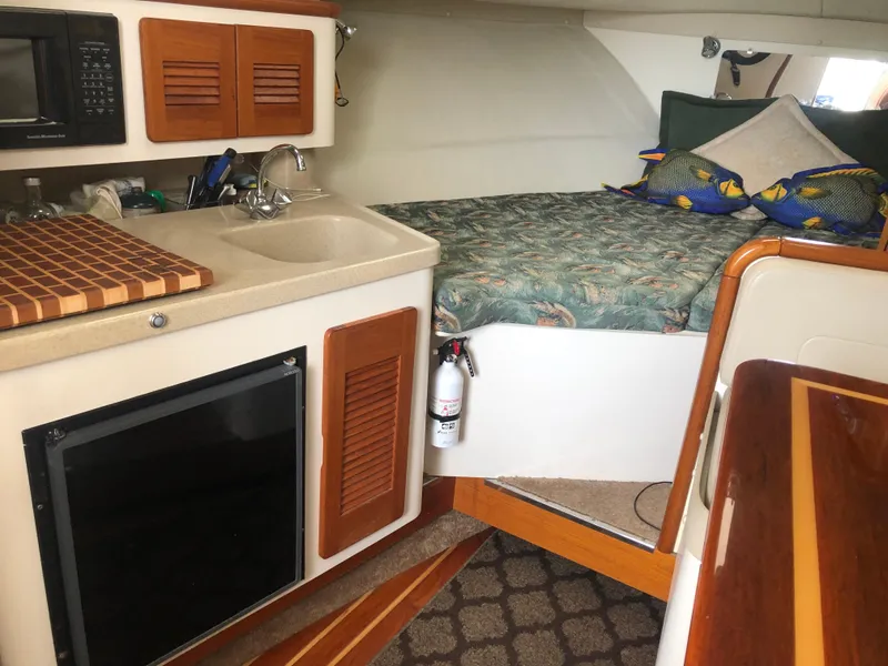 Slide: The Image of 2001 Pursuit 3000 Express cabin with kitchenette, bed, and wooden accents. - 36