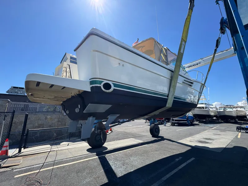 Slide: The Image of 2001 Pursuit 3000 Express boat being lifted at a marina under clear blue sky. - 4