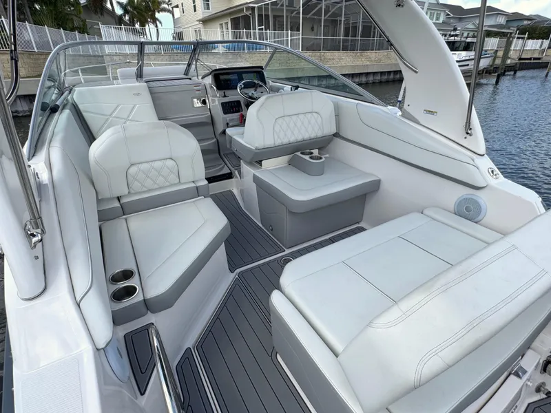 Slide: The Image of 2024 Regal 26 XO boat interior with white seating and modern dashboard, docked by waterfront homes. - 12
