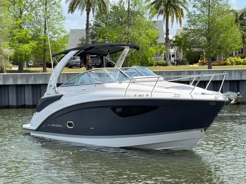 Slide: The Image of 2024 Regal 26 XO boat on a calm waterway, surrounded by lush greenery and palm trees. - 2