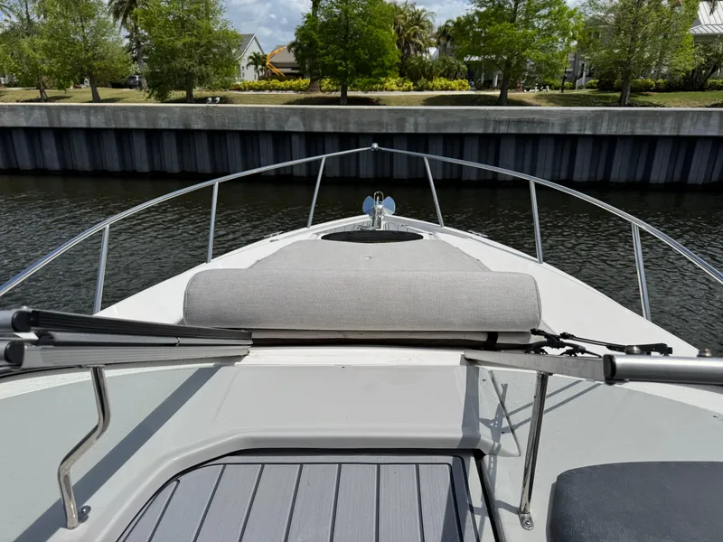 Slide: The Image of 2024 Regal 26 XO boat bow view with railing and seating, docked by a canal. - 23