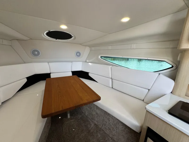 Slide: The Image of 2024 Regal 26 XO cabin interior with white seating and wooden table. - 26