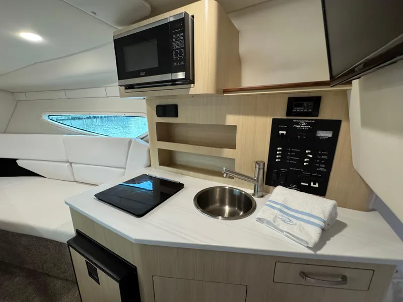 Slide: The Image of 2024 Regal 26 XO boat interior with kitchenette, microwave, sink, and seating area. - 30
