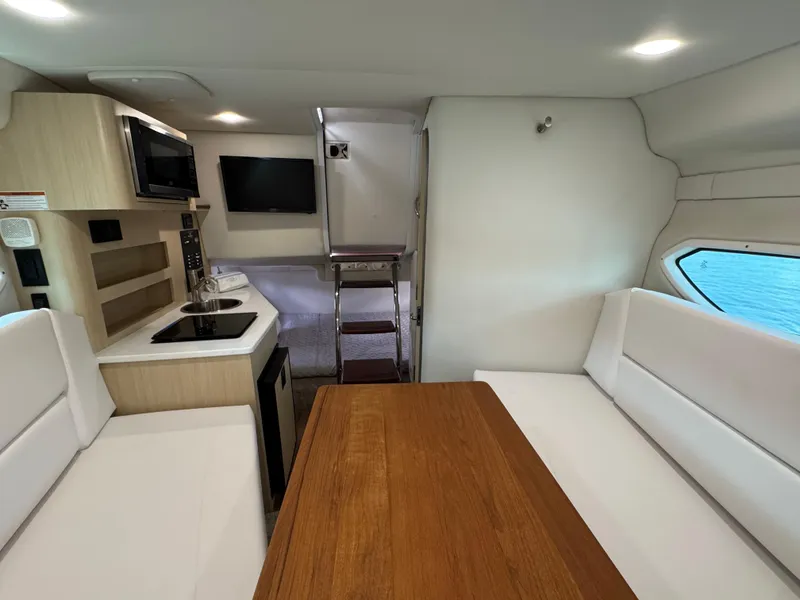 Slide: The Image of 2024 Regal 26 XO cabin interior with kitchenette, seating, and wooden table. - 32