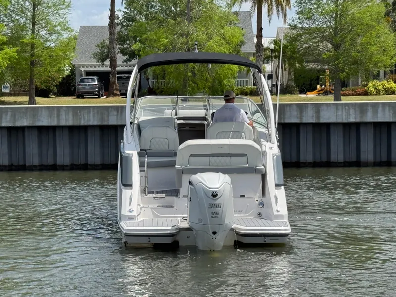Slide: The Image of 2024 Regal 26 XO boat cruising on a calm river near a residential area. - 5