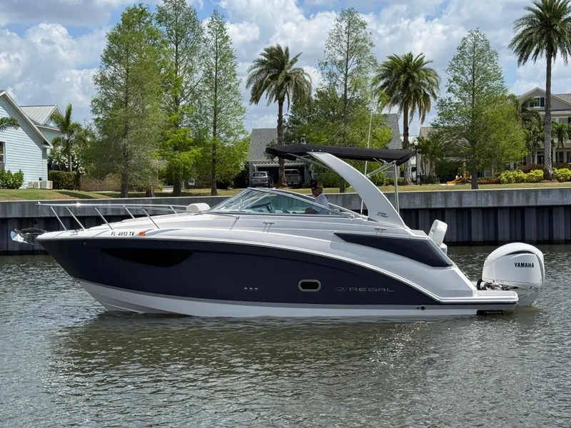 Slide: The Image of 2024 Regal 26 XO boat on a calm waterway with scenic background. - 8