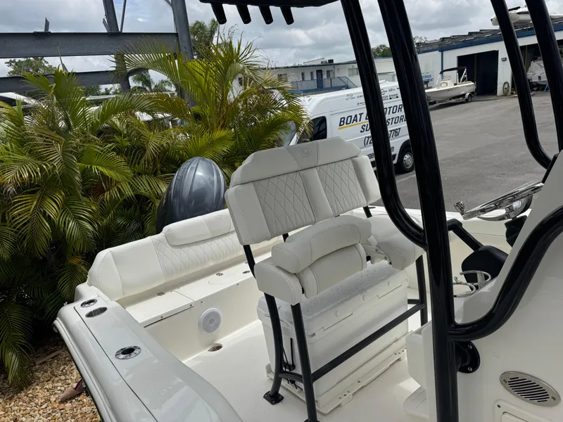 Slide: The Image of 2025 Key West 219 FS boat interior with seating and motor, parked near palm trees. - 27