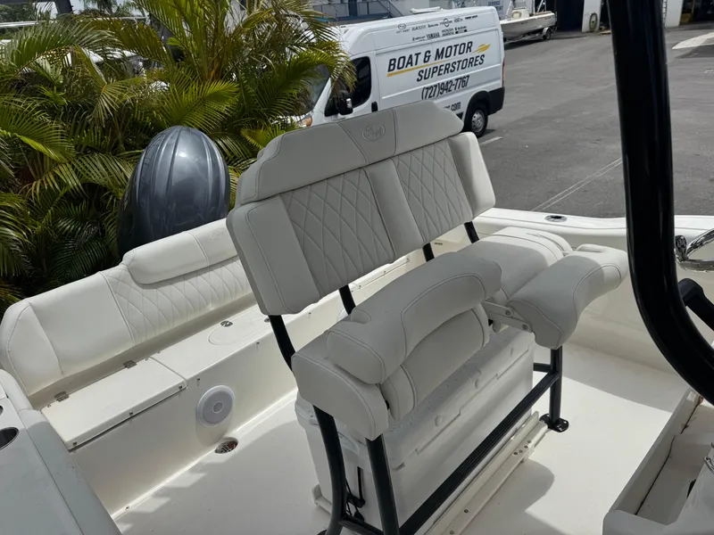 Slide: The Image of 2025 Key West 219 FS boat interior with white seating and motor, parked near dealership. - 28