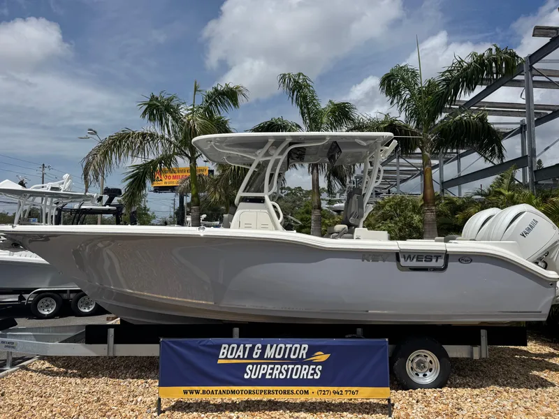 Slide: The Image of 2025 Key West 260 boat displayed at Boat & Motor Superstores, surrounded by palm trees. - 1