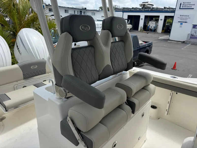 Slide: The Image of 2025 Key West 260 boat seats with gray upholstery and armrests in a marina setting. - 30
