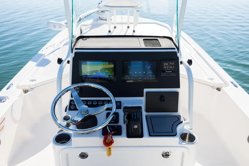 Slide: The Image of 2024 Sea Born FX22 Bay boat dashboard with steering wheel and navigation screens. - 24