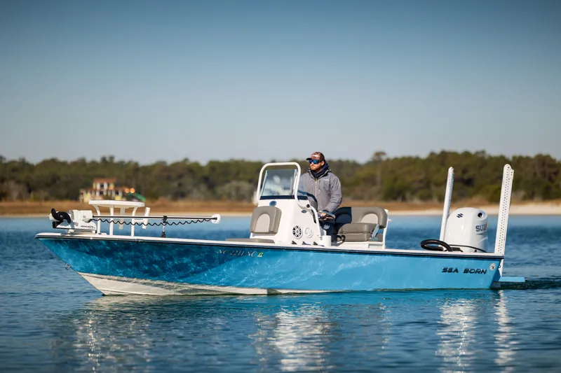 Slide: The Image of 2024 Sea Born FX22 Bay boat on calm water, with a person at the helm. - 3