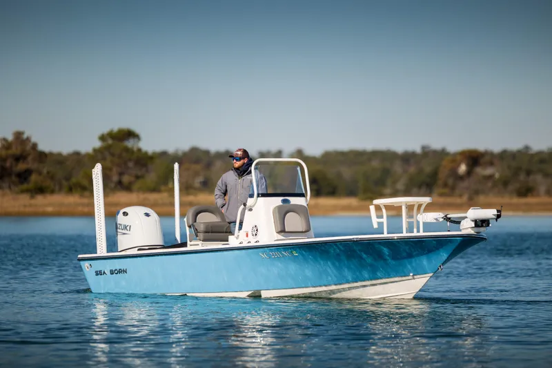 Slide: The Image of 2024 Sea Born FX22 Bay boat on calm water with driver, scenic background. - 4