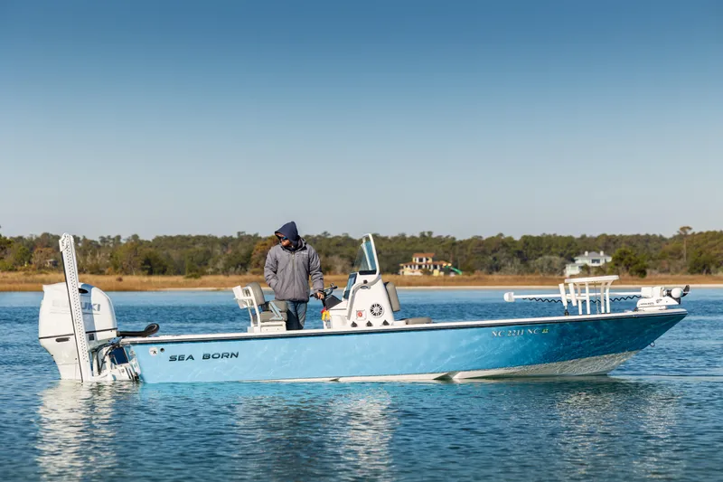 Slide: The Image of 2024 Sea Born FX22 Bay boat on calm water, person standing onboard. - 5