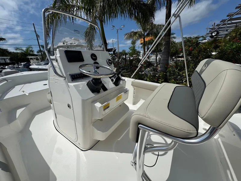Slide: The Image of 2025 Key West 189 FS boat interior with steering console and seating under palm trees. - 16
