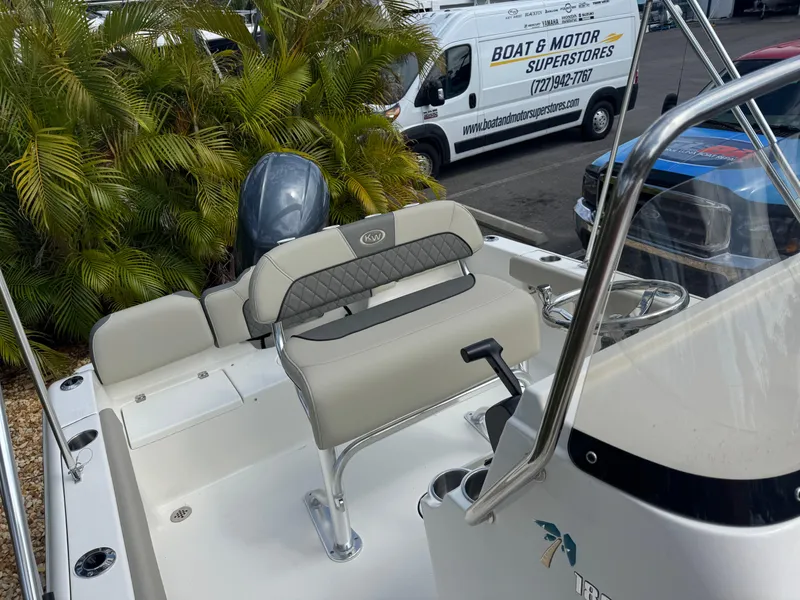 Slide: The Image of 2025 Key West 189 FS boat interior with seating and motor, parked near palm trees. - 29