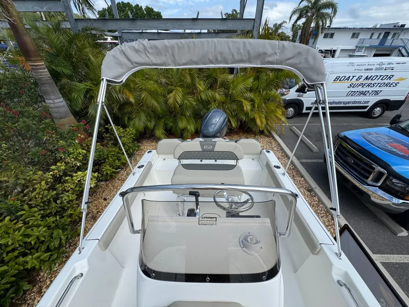 Slide: The Image of 2025 Key West 189 FS boat with canopy, parked near tropical plants and vehicles. - 31