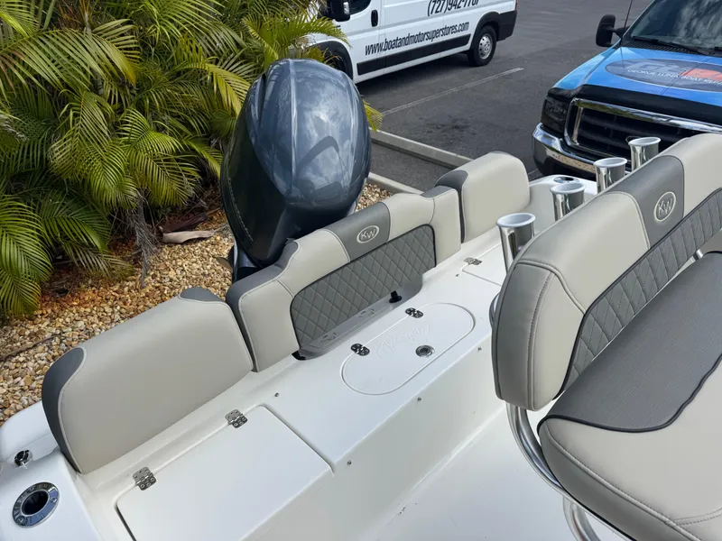 Slide: The Image of 2025 Key West 189 FS boat interior with seating and motor, parked near tropical plants. - 33