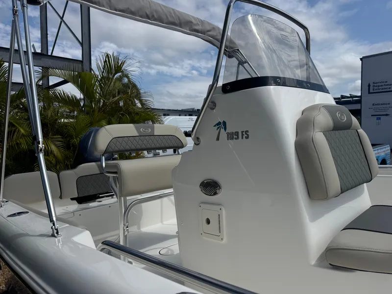 Slide: The Image of 2025 Key West 189 FS boat interior with cushioned seating and console, under a clear sky. - 6