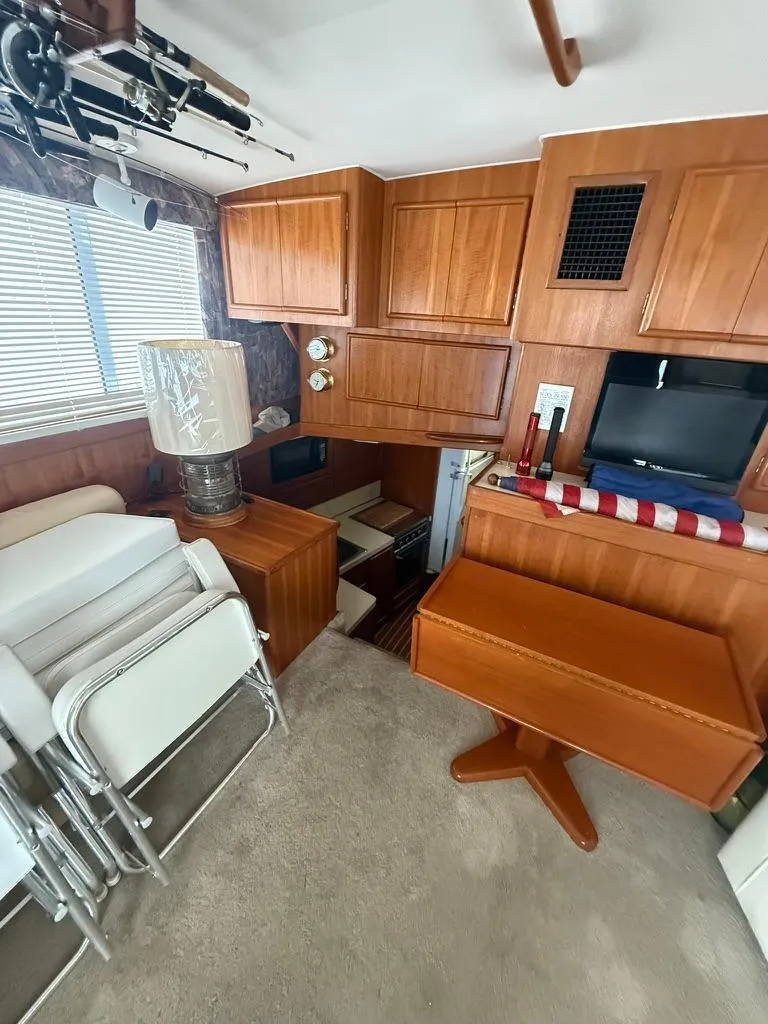 Slide: The Image of 1989 Post 43 Sport Fisherman interior with wooden cabinets, folding chairs, and a small TV. - 14