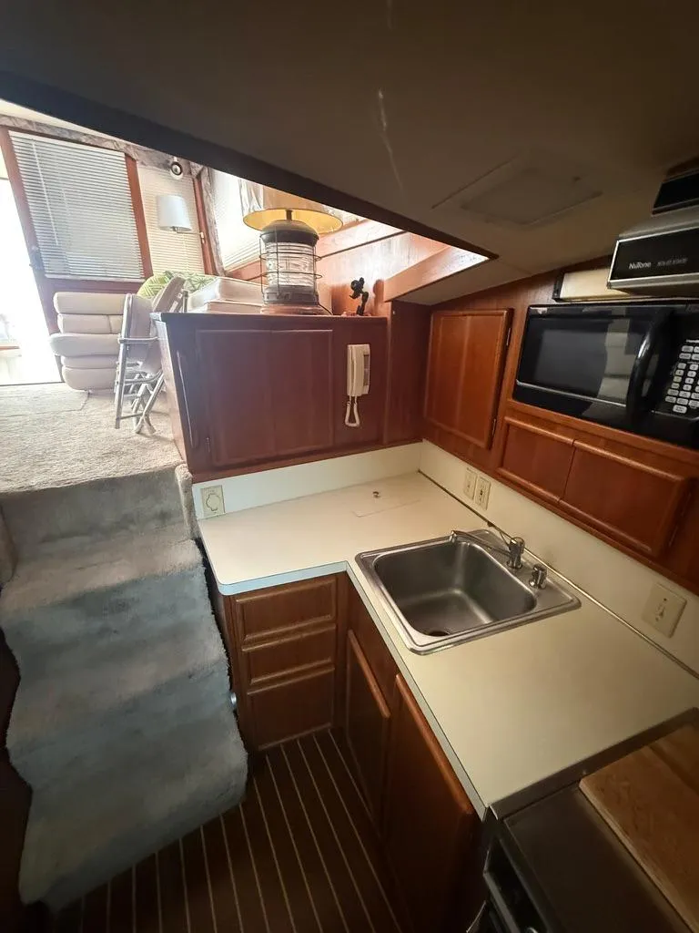 Slide: The Image of 1989 Post 43 Sport Fisherman interior with kitchen, sink, microwave, and stairs leading to living area. - 16